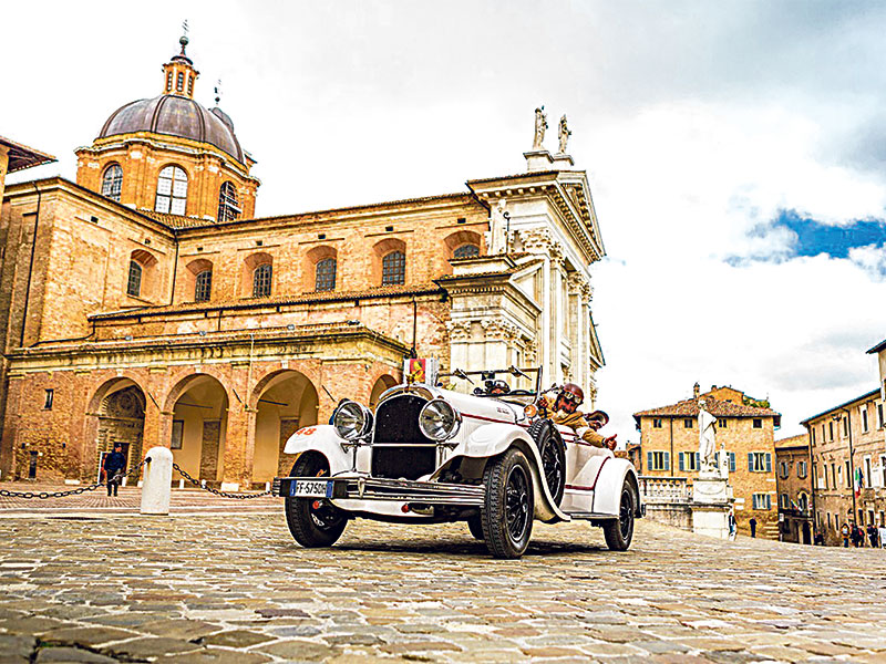 One of hundreds of vintage sports cars passing through an Italian town square during the 1000 Miglia 2019.