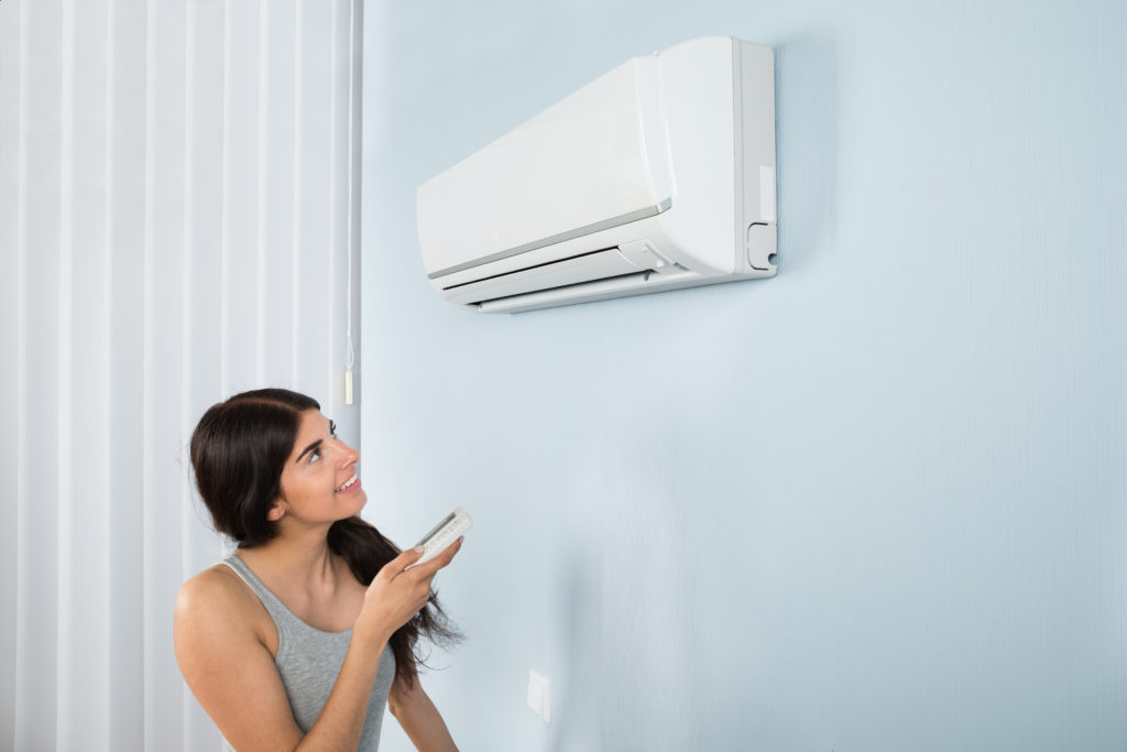 Image of a young woman holding the air conditioner remote control.