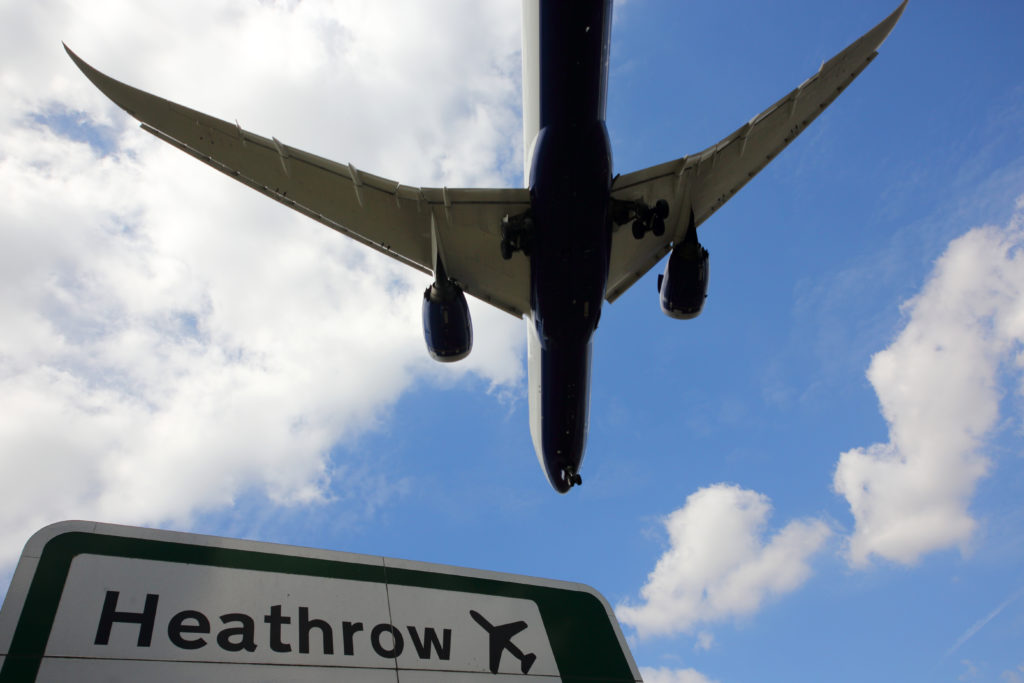 Image of a plane flying over London Heathrow Airport.