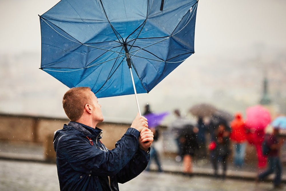Image of a man's umbrella blowing in the wind.