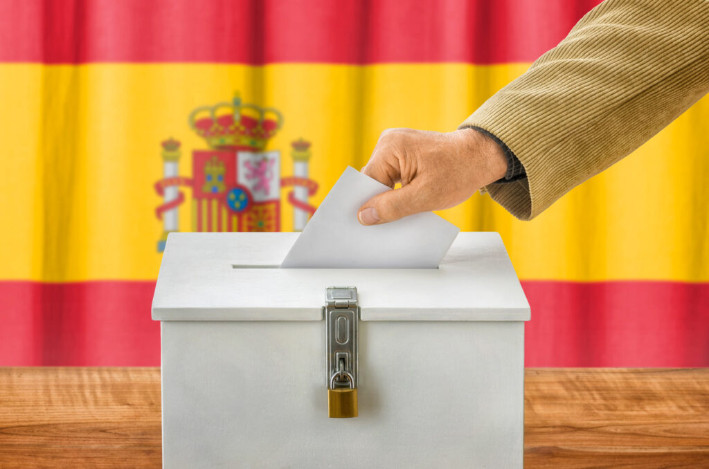 Image of a person putting a paper into the ballot box in Spain.
