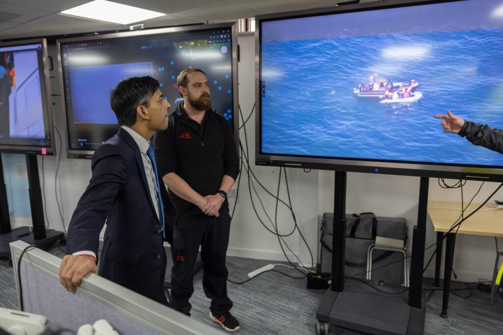 UK prime minister looks at screen of channel crossings