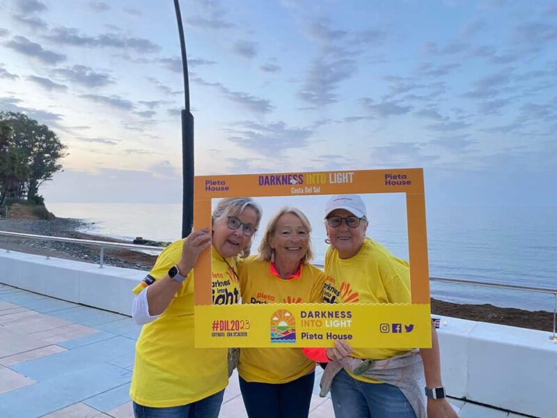 walkers pose in front of the ocean with a giant photo frame