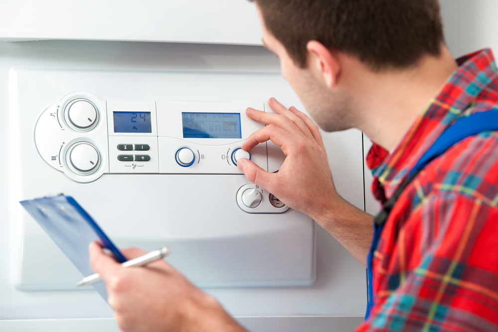 A technician adjusting the temperature on a gas boiler