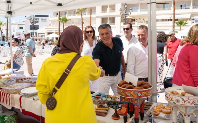 the mayor of Nerja reaches over a stall selling Moroccan goods.