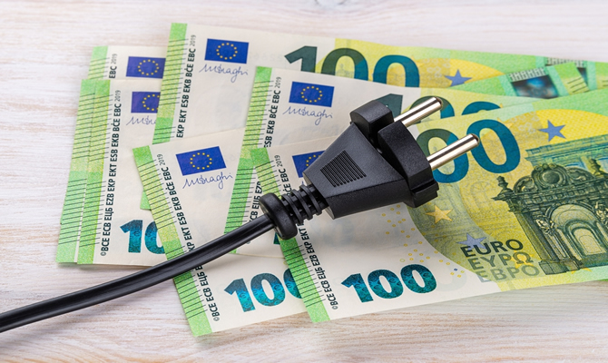 Image of electric plug lying on €100 notes.