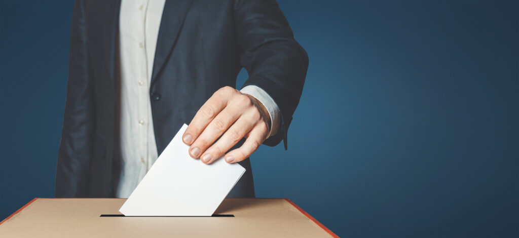 Image of a man placing a voting paper in a ballot box.