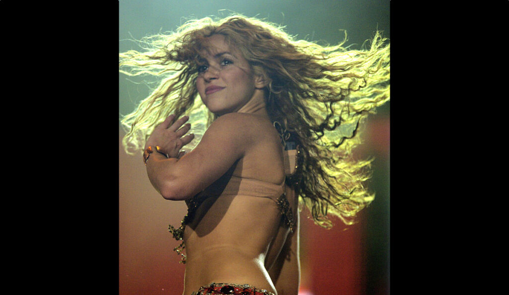 Shakira turns her head as her hair spirals around her on stage