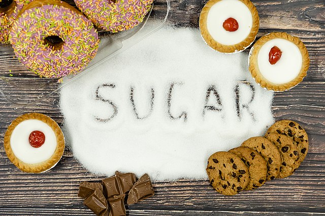 The word sugar is written in sugar and surrounded by cakes, biscuits and doughnuts