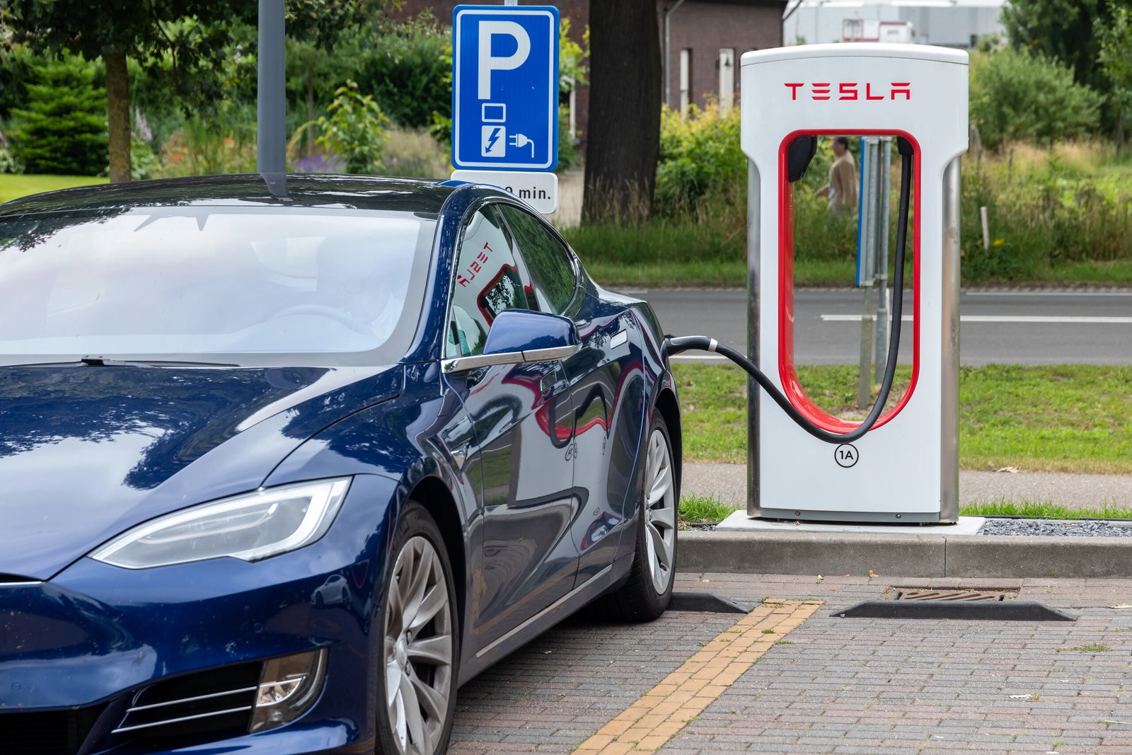 A blue Tesla charging in a parking space