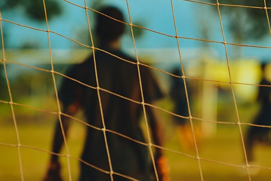 Image of a goalkeeper through the net.