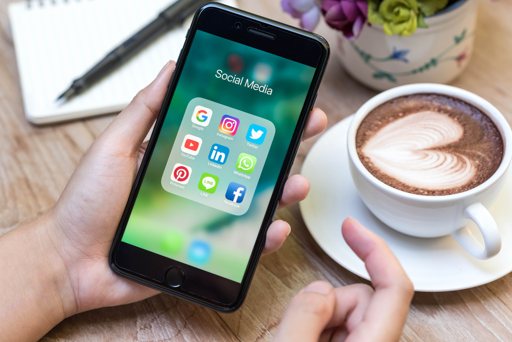 Telephone with social media apps open with coffee in the backround