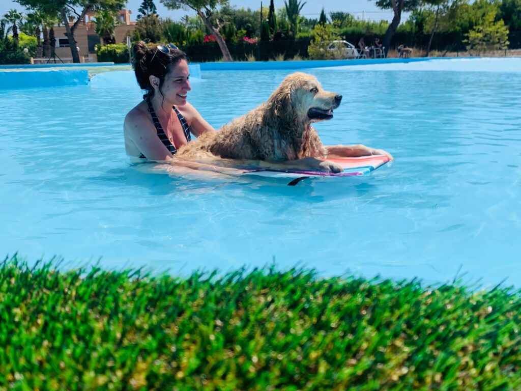 A woman in a pool with her dog