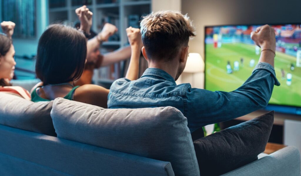 People on a sofa watching football on TV