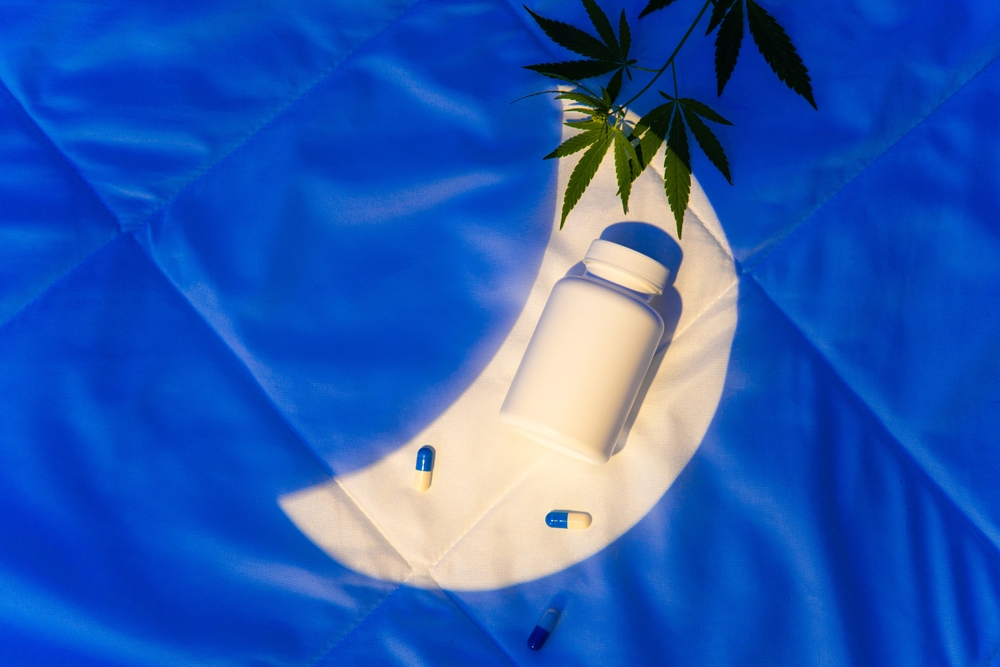 Moon shape on a bed cover with bottle of capsules with hemp leaf