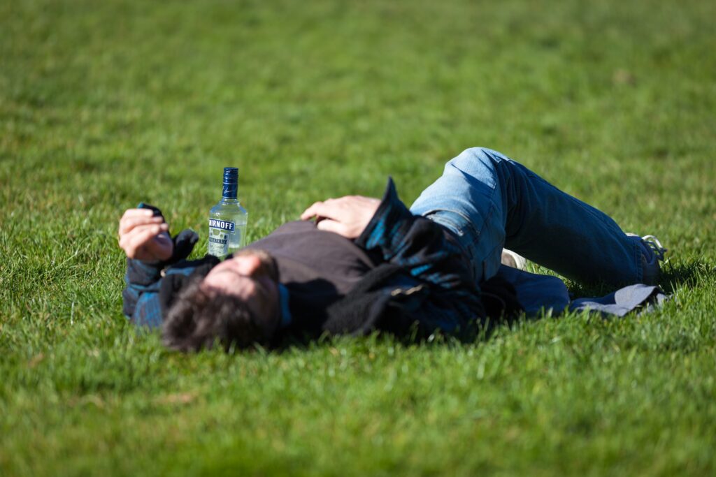 Man passed out on grass with bottle of vodka