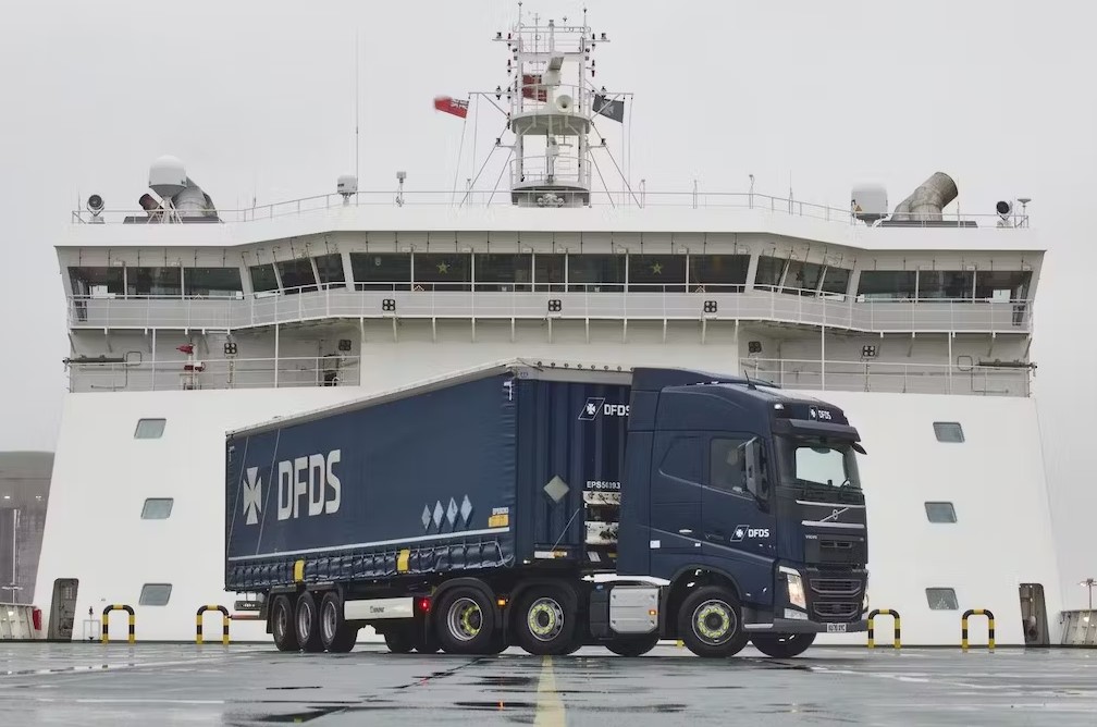Large dark blue DFDS truck on deck of cargo ship