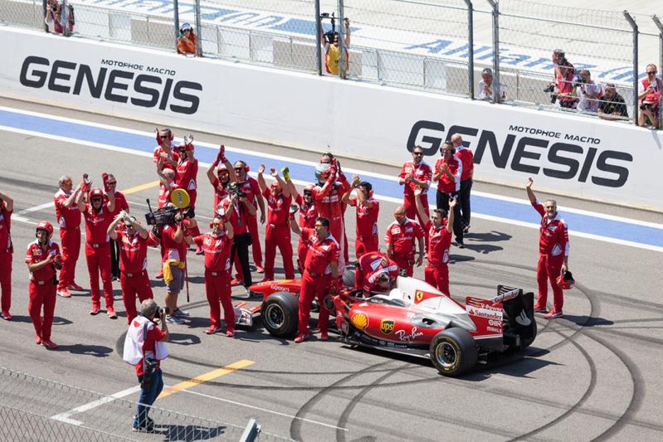 Ferrari racing car on a track with the pitstop team around the car celebrating on a win