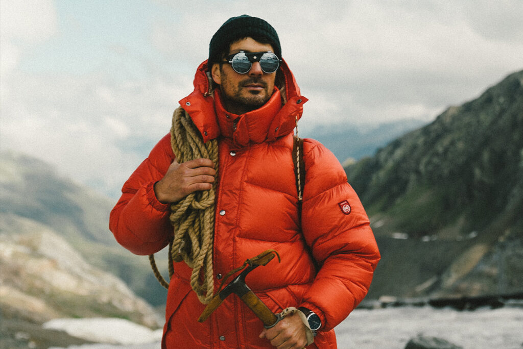 Man in an bright orange Gorpcorp jacket with climbing rope and tools