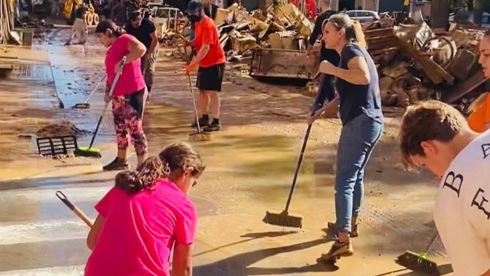 Men and women helping to clean up the streets after severe flooding