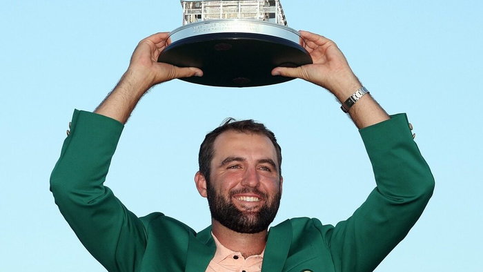 Smiling young man in green jacket holds trophy above his head. Euro Weekly News.