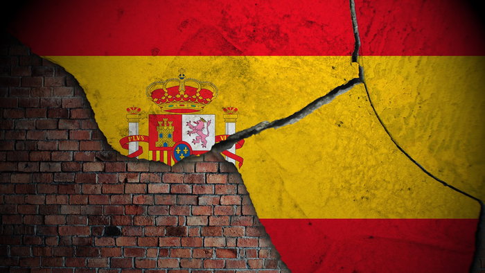Cracked Spanish flag on a brick wall, symbolizing the effects of an earthquake