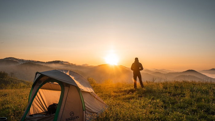a person camping, looking at the sun