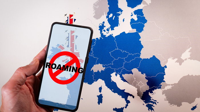 Hand holding smartphone showing 'No Roaming' symbol over UK map, highlighting Brexit roaming charges issue.
