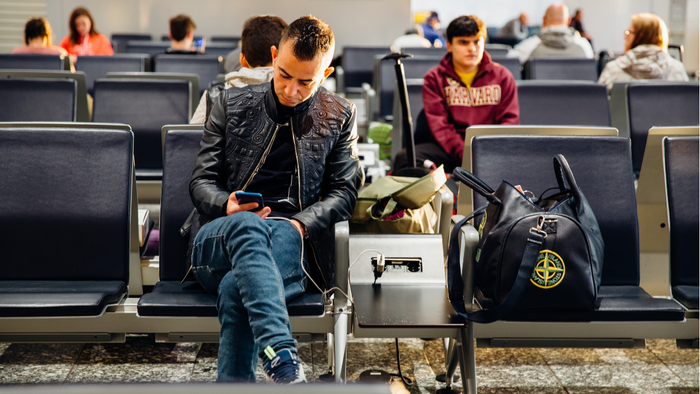 Man charging phone at airport gate with power bank