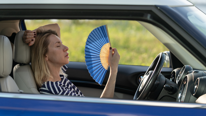 Woman fanning herself inside a parked car during a heatwave in Spain.