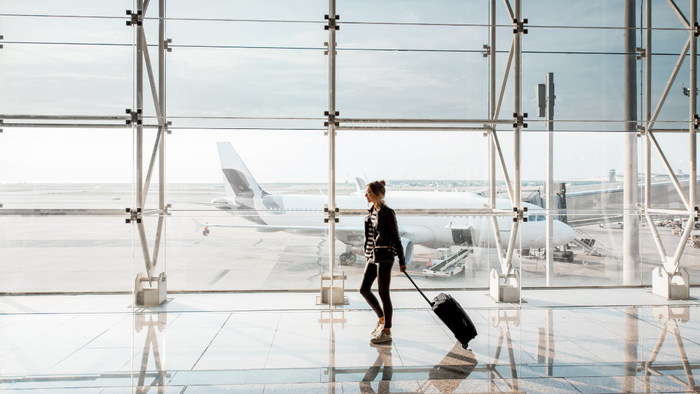 Traveller walking through a Spanish airport terminal with a plane outside