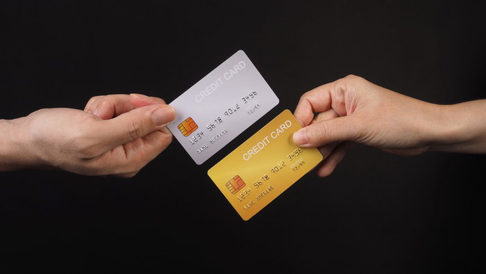 Two hands holding credit cards with a black backdrop
