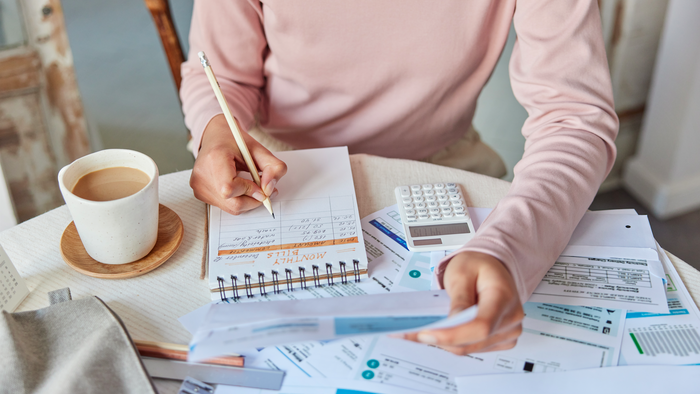 Woman at a table calculating expenses on a notepad