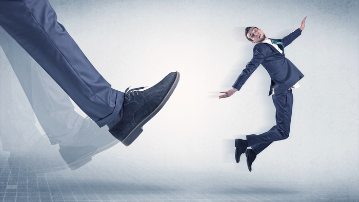 Large foot kicking a small business man