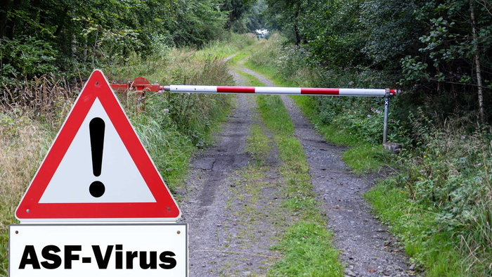 A warning sign with a barrier on a dirt track road