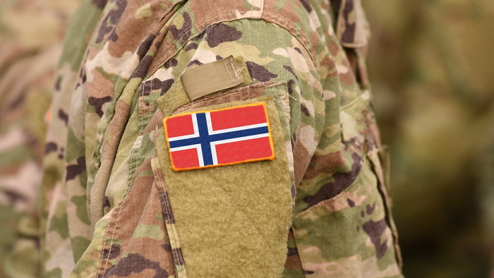 Norwegian military uniform with national flag patch, symbolising defence preparedness.