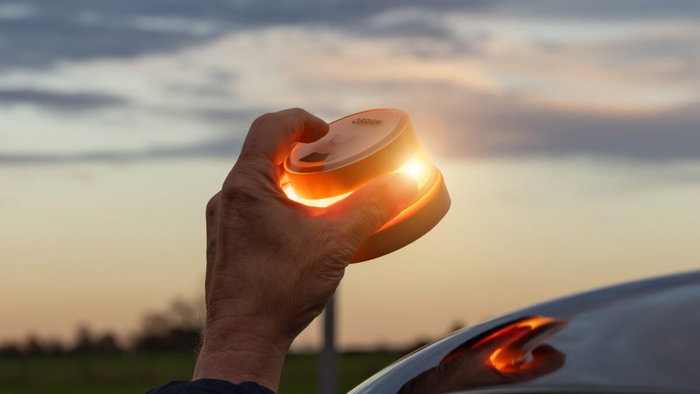 Hand placing a V16 beacon on the roof of a car