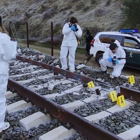 Investigators look at broken section of track and burn marks.