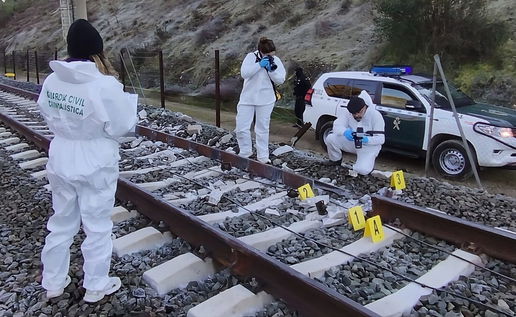Investigators look at broken section of track and burn marks.