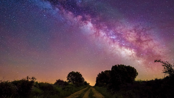 Clear night sky filled with stars and the Milky Way above a rural landscape.