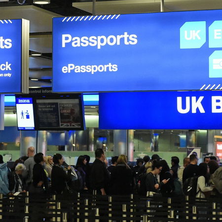 Travellers queuing at UK passport control at an airport border checkpoint