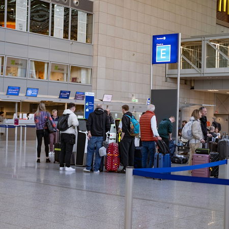 Travellers queue at airport check-in desks before a flight