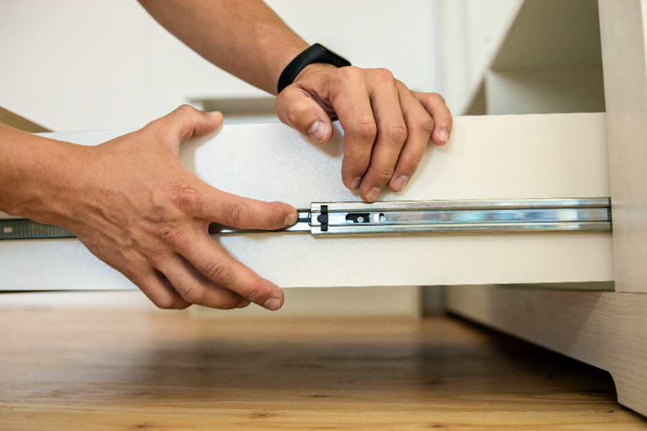 Close up view of a carpenters hands installing a drawer rail