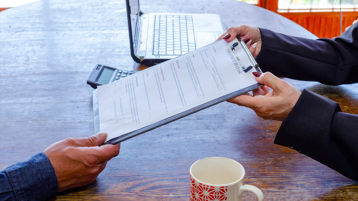 Contract being handed over a desk to sign