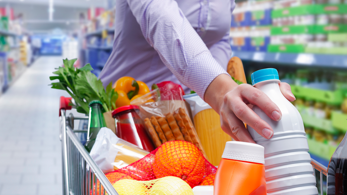 Woman places a bottle of milk in a shopping trolley
