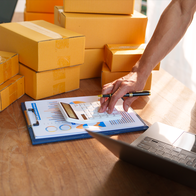 Man using a calculator with boxes next to him and a laptop