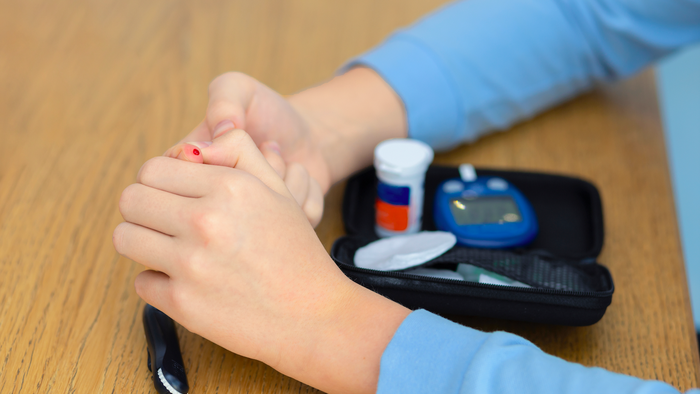 Young person pricking finger for sugar level test