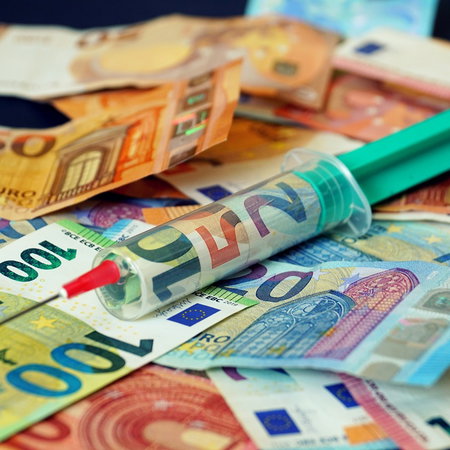Euro banknotes with a syringe symbolising financial aid and Spain’s Ingreso Mínimo Vital support system