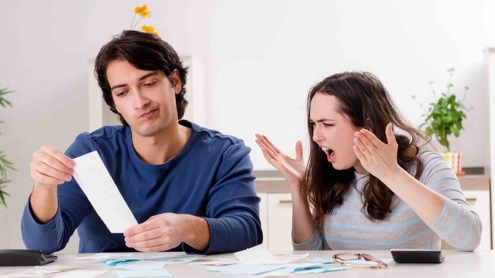 Couple at home looking stressed while reviewing bills and paperwork at a table