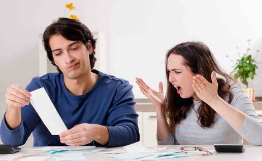 Couple at home looking stressed while reviewing bills and paperwork at a table